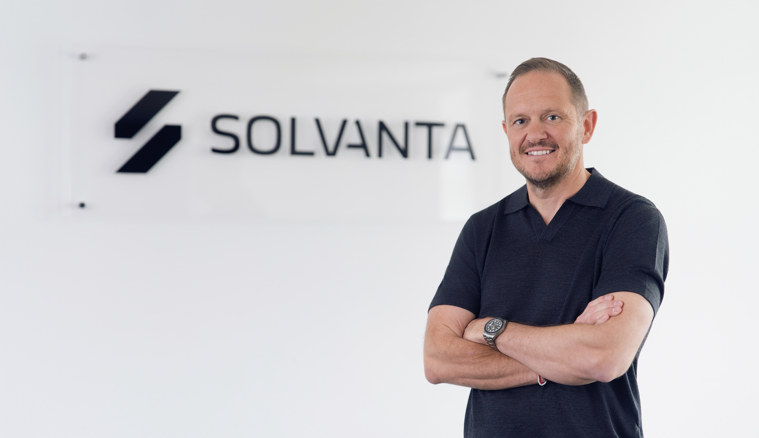 Person standing with arms crossed in front of Solvanta logo