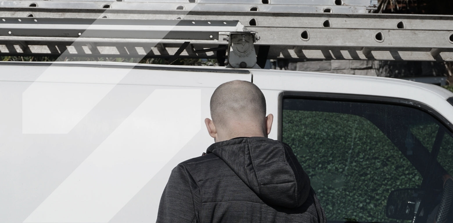 Man getting into work van with ladders on top